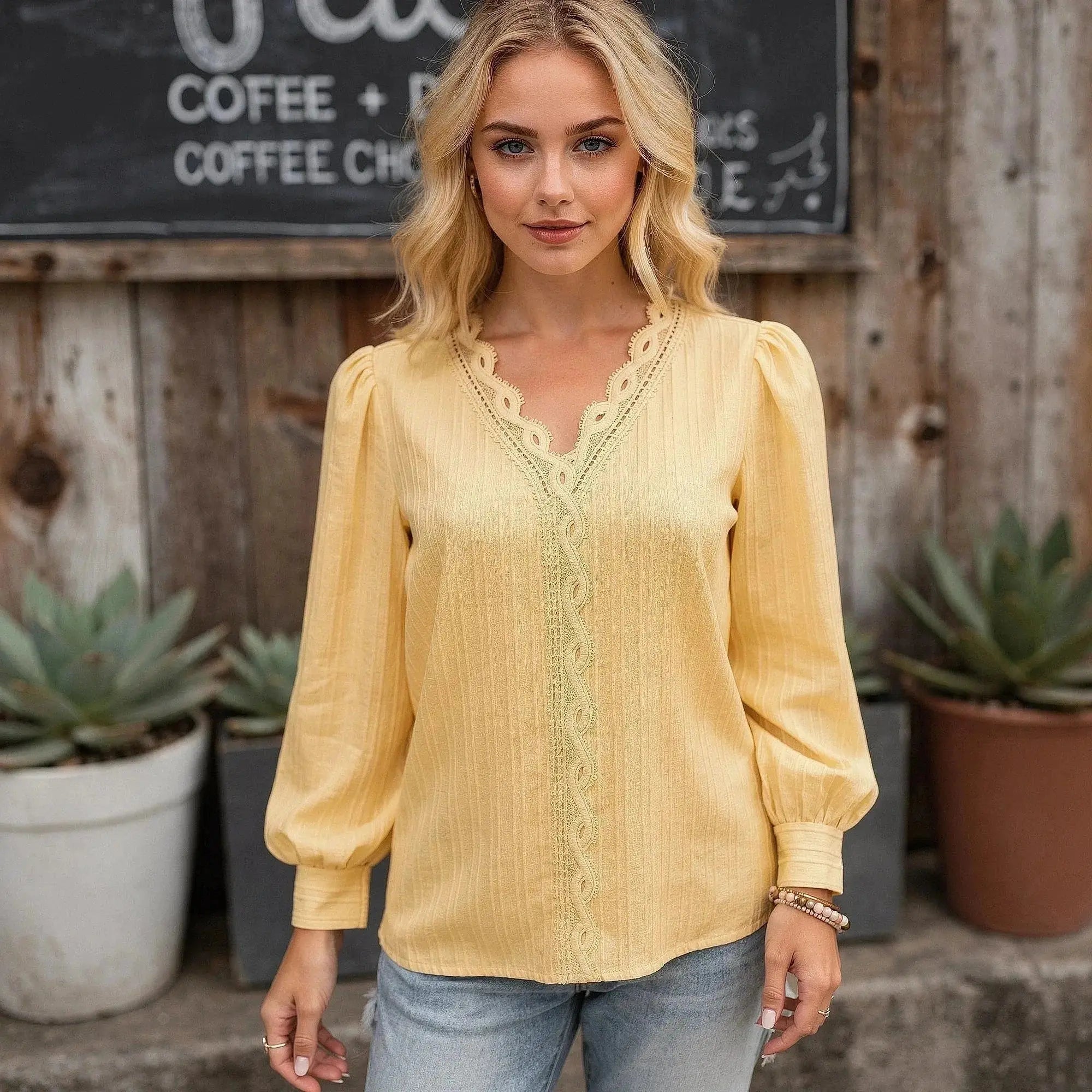 Woman wearing a yellow chiffon top with lace trim, standing outdoors, hands