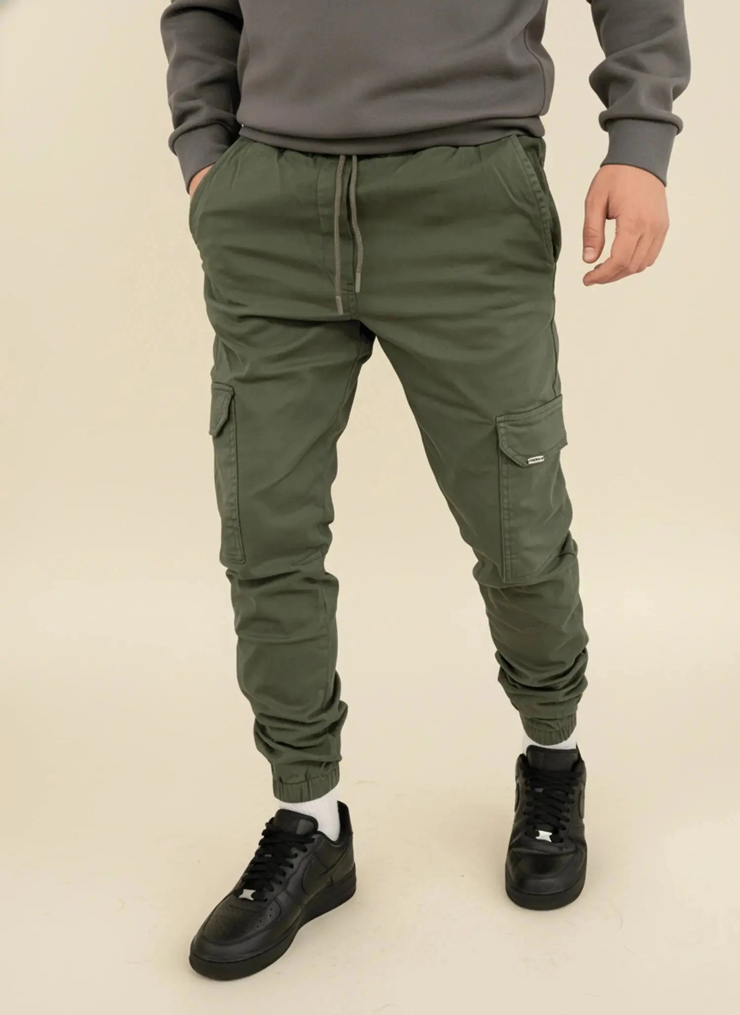 View of modern slim tapered cargo pants in olive green, featuring multiple pockets and a soft cotton blend material
