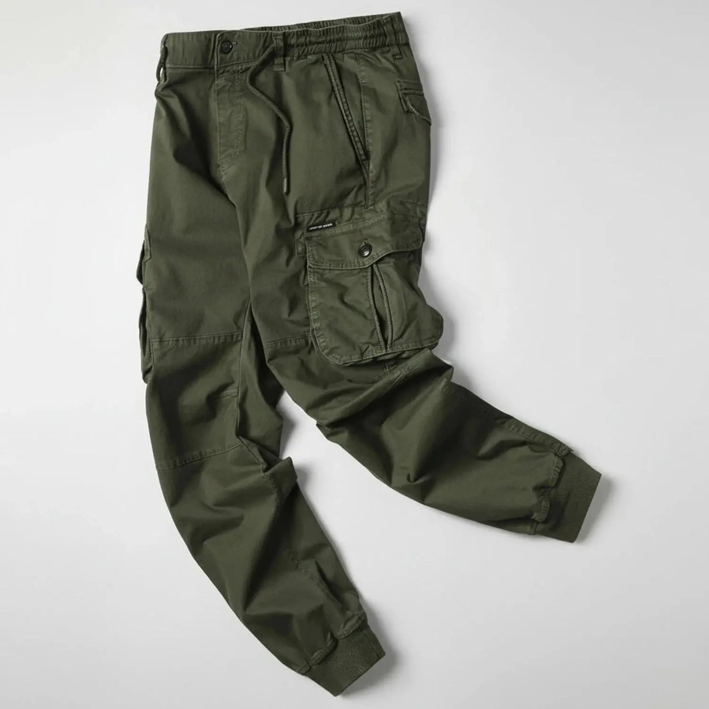 View of relaxed utility summer cargo jogger pants in olive green, featuring multiple pockets and a comfortable waistband