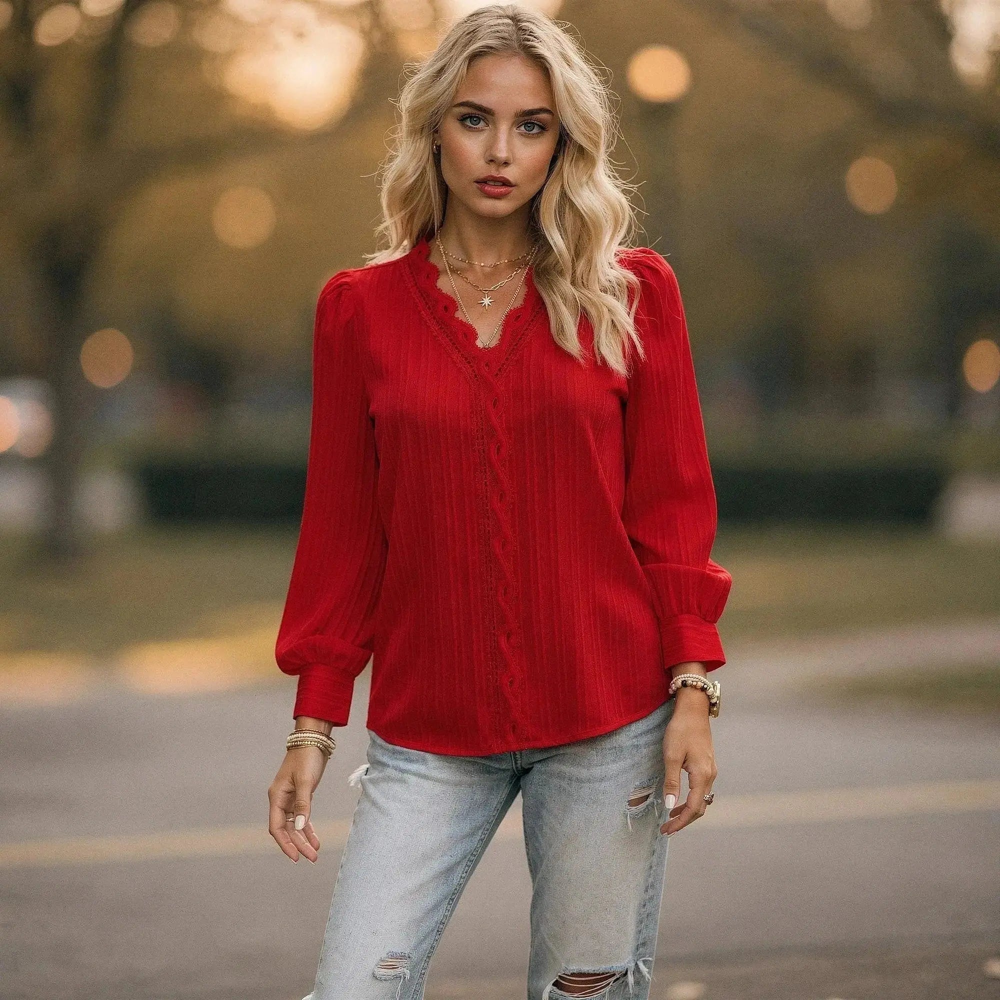 Woman wearing a red chiffon top with long sleeves and scalloped neckline, standing outdoors