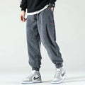 Man wearing grey corduroy joggers with elastic cuffs, standing sideways, paired with high top sneakers