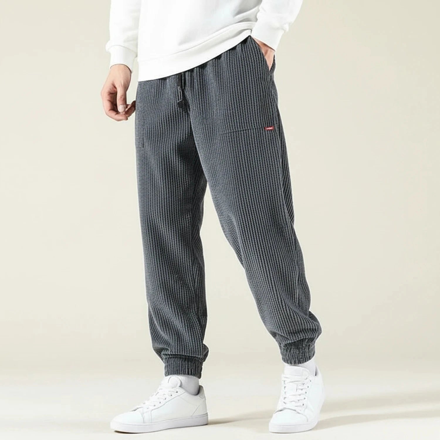 View of relaxed fit jogger pants in dark gray, featuring an elastic waistband and tapered legs