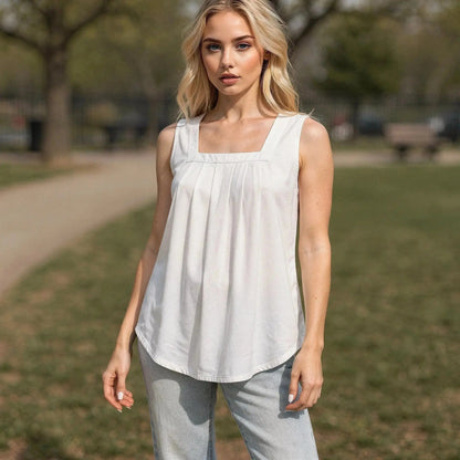 Woman wearing white sleeveless top with square neckline, standing outdoors, hands