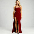 Woman wearing a red fitted maxi dress with high slit, standing, facing forward, and black heels
