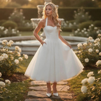 Woman wearing a white halter neck midi dress standing in a garden surrounded