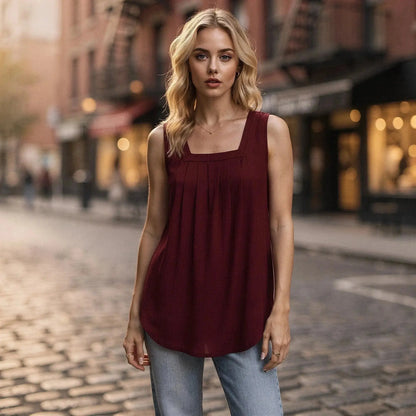 Woman wearing a sleeveless burgundy top with square neckline, standing on a cobblestone street
