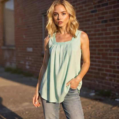 Woman wearing a light green sleeveless midi top with pleats, standing outdoors in sunlight