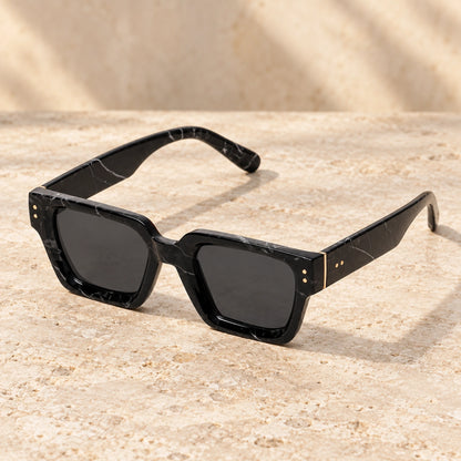 Rivet Black Marble Charcoal sunglasses, complete pair on a warm neutral stone surface. — view 14