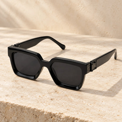 Medium Black Charcoal sunglasses, complete pair on a warm neutral stone surface. — view 5